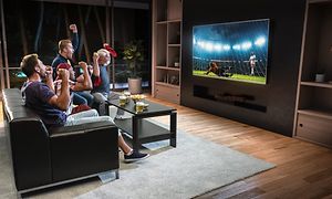 Mænd i en stue der ser TV på en stor skærm
