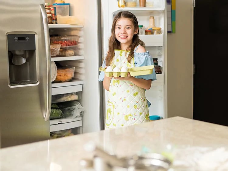 Pige med æg foran køleskabet
