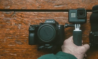 SLR kamera action kamera og en holder på et bord