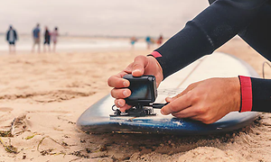 en mand monterer sit actionkamera på sit surfboard