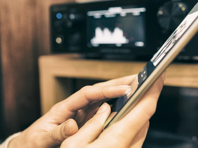 Person der streamer musik fra en tablet til lydsystem i baggrunden