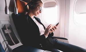 Kvinde med støjreducerende høretelefoner slapper af på flyet