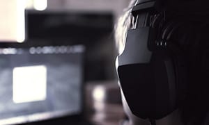 En person med et gaming headset og en skærm set fra siden