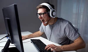 Mand der skriger af sin skærm mens han spiller med et gaming headset