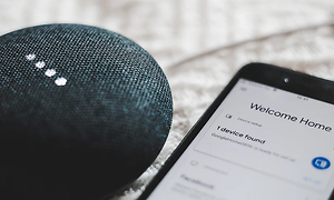 Google Home Mini og smartphone på et bord