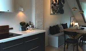 sorte skuffer og skabe i et epoq køkken i en lejlighed med skrå vægge