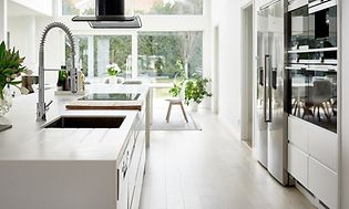 hvidt køkken med køkkenø og amerikanske køleskabe